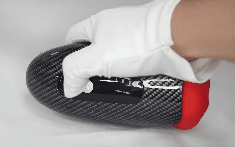 Hand holding compact electric male masturbator with textured shell and single button control